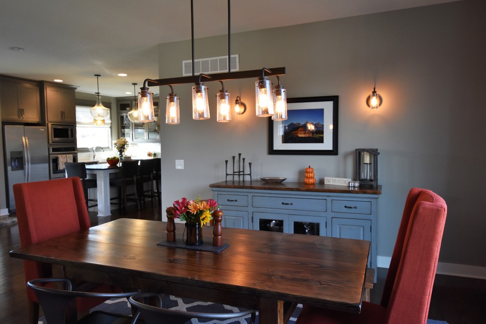 Immagine di una sala da pranzo aperta verso la cucina stile americano di medie dimensioni con pareti grigie, parquet scuro, camino classico e cornice del camino in pietra