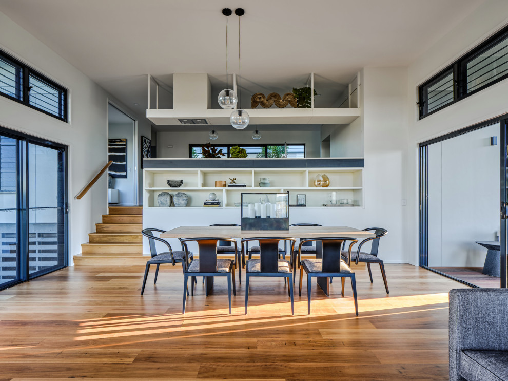 Inspiration pour une salle à manger ouverte sur le salon design avec un mur blanc, un sol en bois brun et un sol marron.
