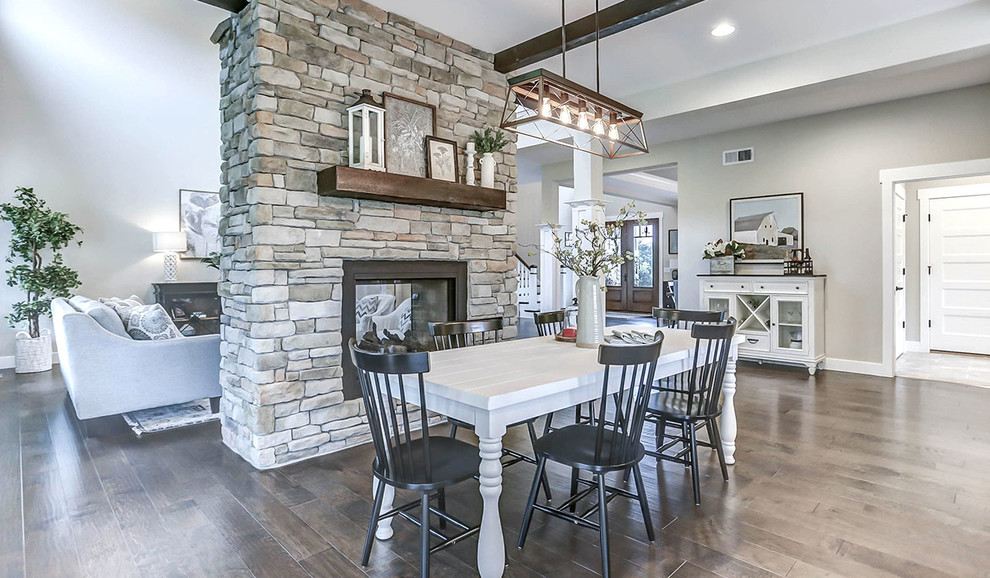 Huge country medium tone wood floor kitchen/dining room combo photo in Other with gray walls, a two-sided fireplace and a stone fireplace