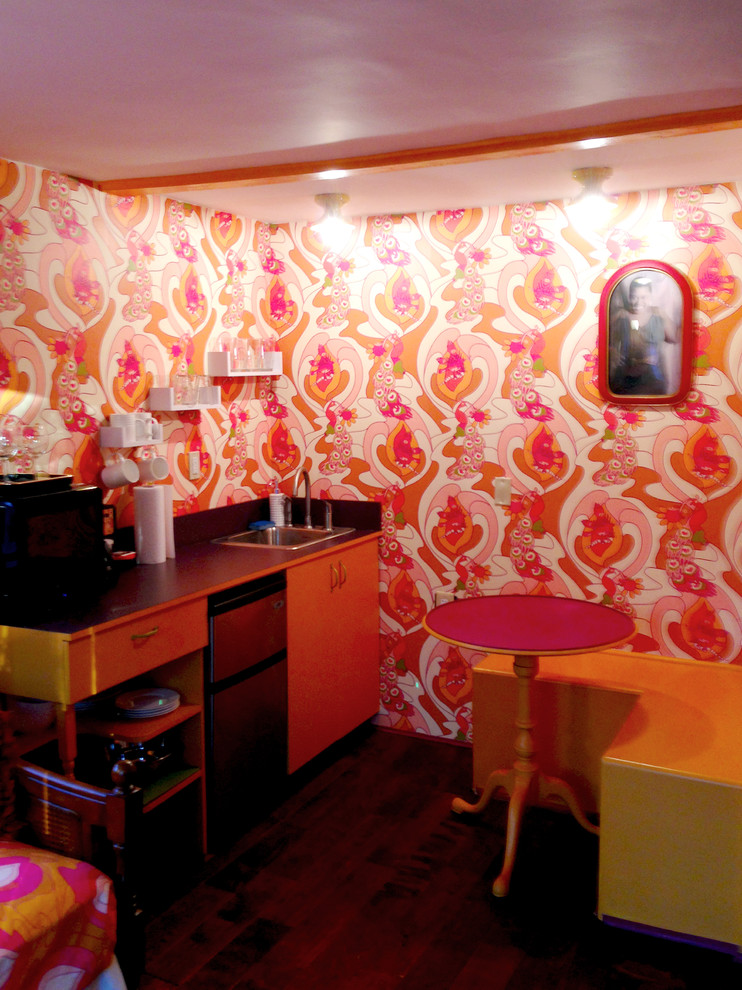 Cette image montre une petite salle à manger ouverte sur la cuisine bohème avec un mur multicolore et parquet foncé.