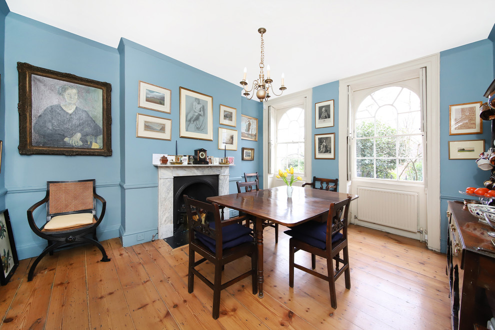 Foto de comedor clásico de tamaño medio cerrado con paredes azules, todas las chimeneas y suelo de madera clara