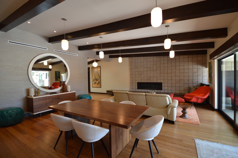 Aménagement d'une grande salle à manger ouverte sur le salon rétro avec un mur multicolore, un sol en bois brun et aucune cheminée.