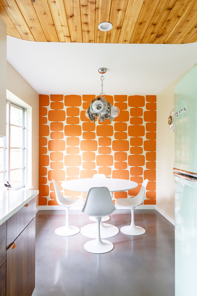 オースティンにあるミッドセンチュリースタイルのおしゃれなダイニングキッチン (コンクリートの床、オレンジの壁、暖炉なし、グレーの床) の写真