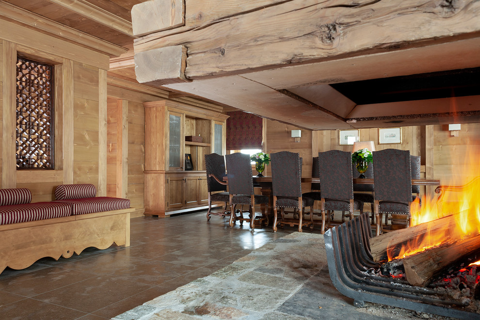 他の地域にあるエクレクティックスタイルのおしゃれなダイニング (セラミックタイルの床、吊り下げ式暖炉、木材の暖炉まわり、茶色い床) の写真