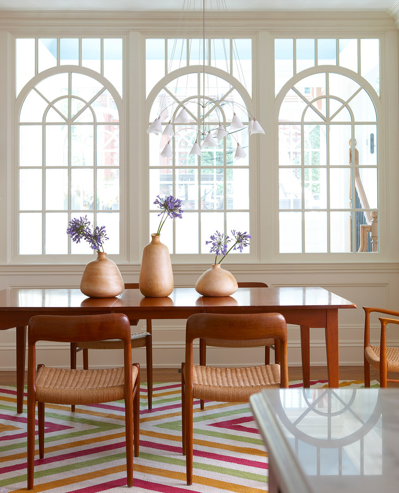 Immagine di una piccola sala da pranzo aperta verso la cucina vittoriana con pareti bianche e parquet chiaro