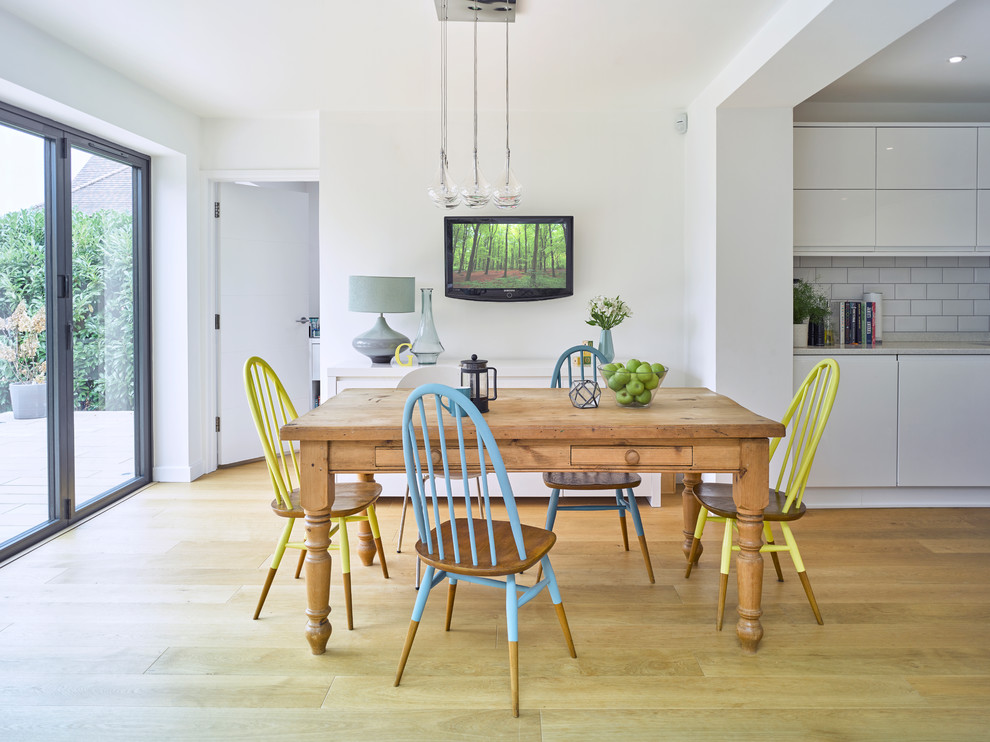 Exemple d'une salle à manger ouverte sur la cuisine tendance de taille moyenne avec un mur blanc, un sol en bois brun et un sol marron.
