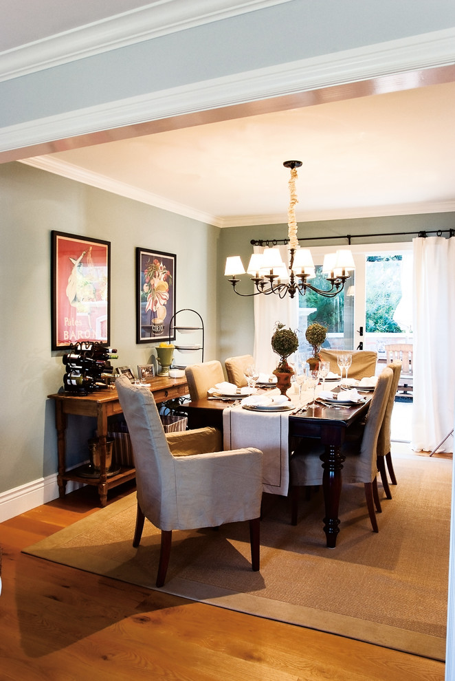 Cette photo montre une salle à manger ouverte sur la cuisine chic de taille moyenne avec un sol en bois brun, un mur vert et aucune cheminée.