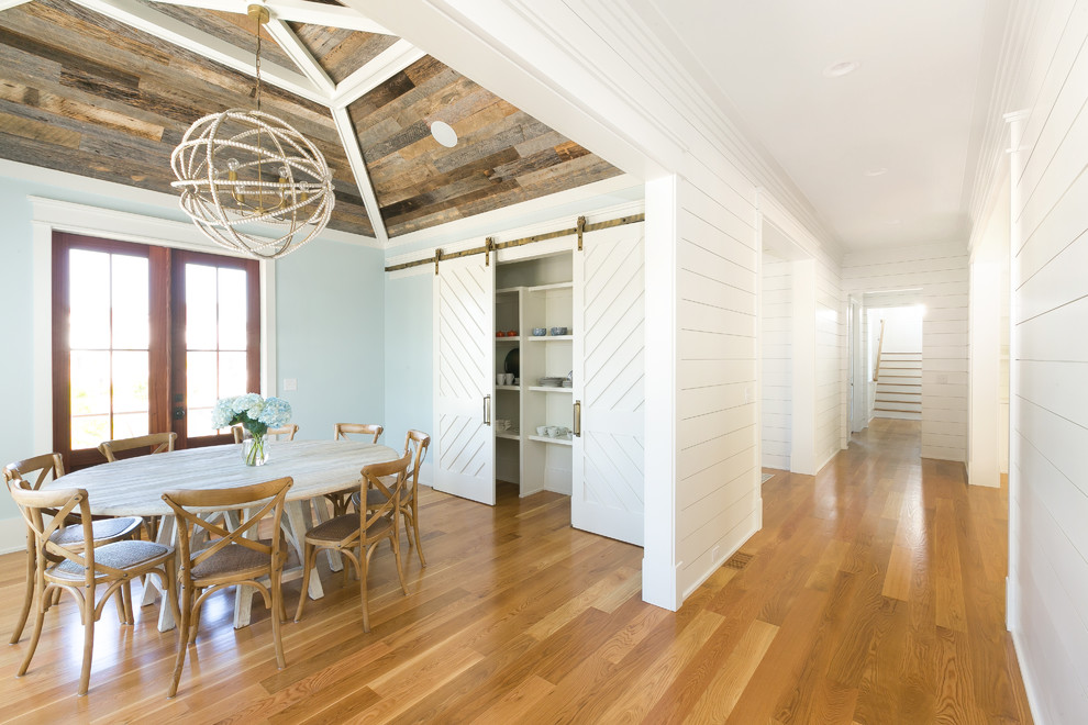 Foto di una grande sala da pranzo country chiusa con pareti blu, pavimento in legno massello medio, nessun camino e pavimento marrone