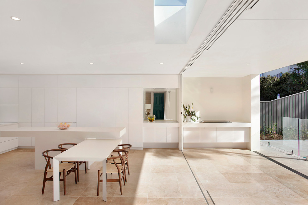Idées déco pour une salle à manger ouverte sur la cuisine contemporaine avec un sol en travertin et un mur blanc.