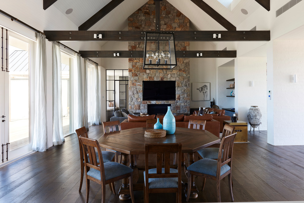 Cette image montre une salle à manger ouverte sur le salon traditionnelle avec un mur blanc, parquet foncé, une cheminée standard et un manteau de cheminée en pierre.