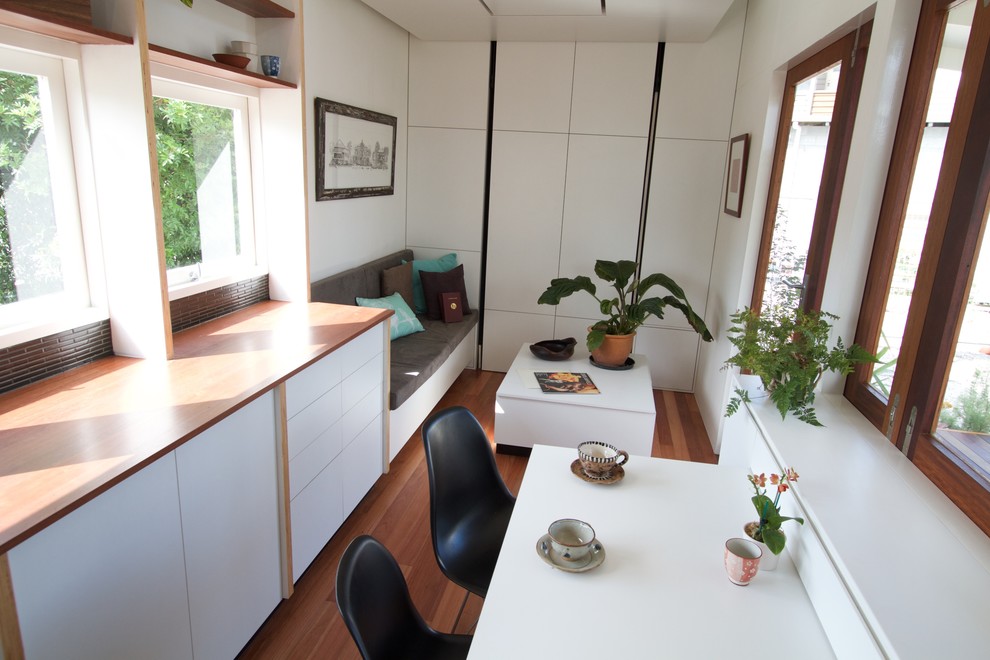 Modelo de comedor de cocina minimalista pequeño con paredes blancas y suelo de madera en tonos medios