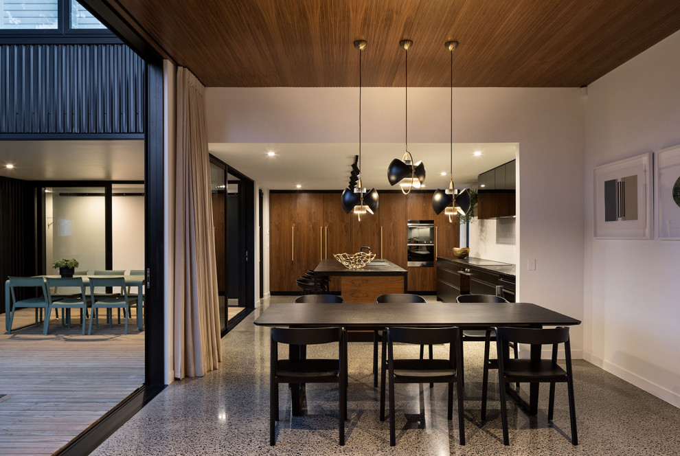 Immagine di una grande sala da pranzo aperta verso la cucina minimalista con pareti bianche, pavimento in cemento e soffitto in perlinato
