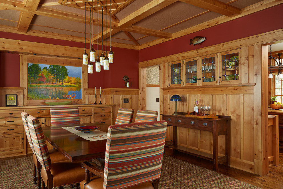 Foto di una sala da pranzo rustica chiusa con pareti rosse, pavimento in legno massello medio e nessun camino