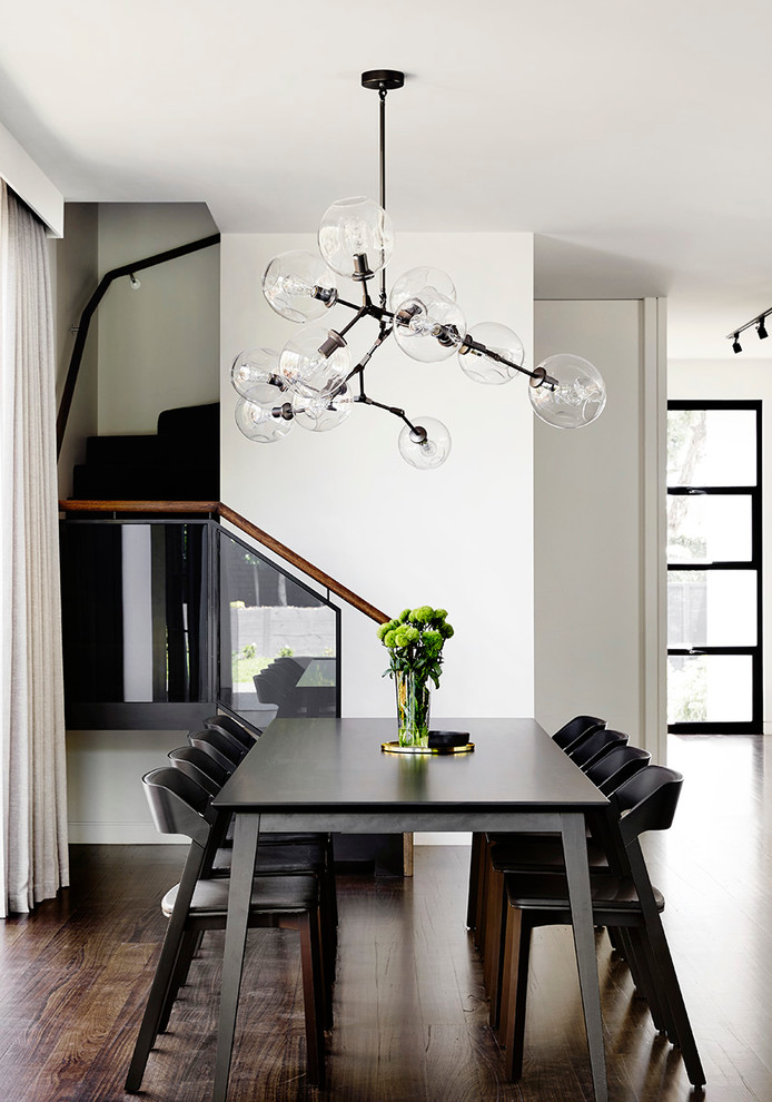 Стильный дизайн: столовая в современном стиле с белыми стенами и темным паркетным полом - последний тренд