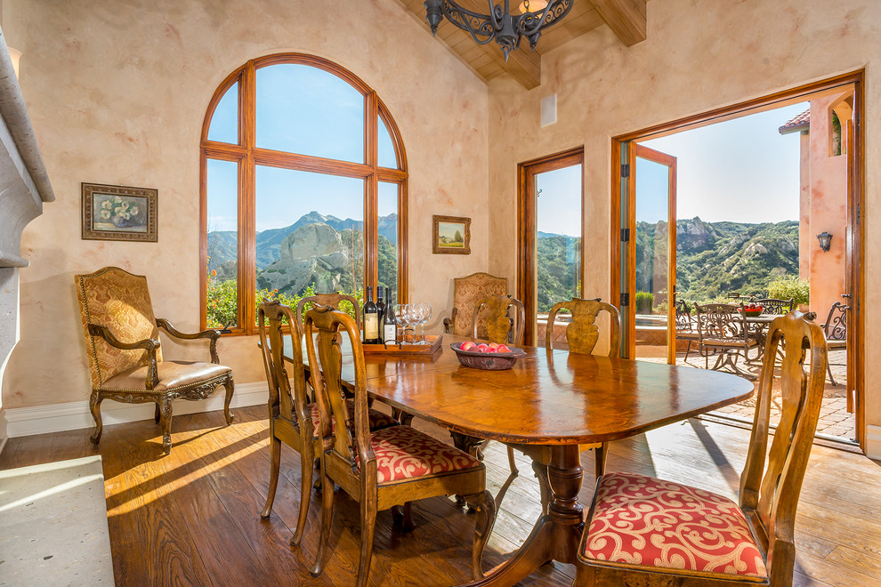 Large tuscan medium tone wood floor and brown floor enclosed dining room photo in Los Angeles with beige walls, a standard fireplace and a concrete fireplace