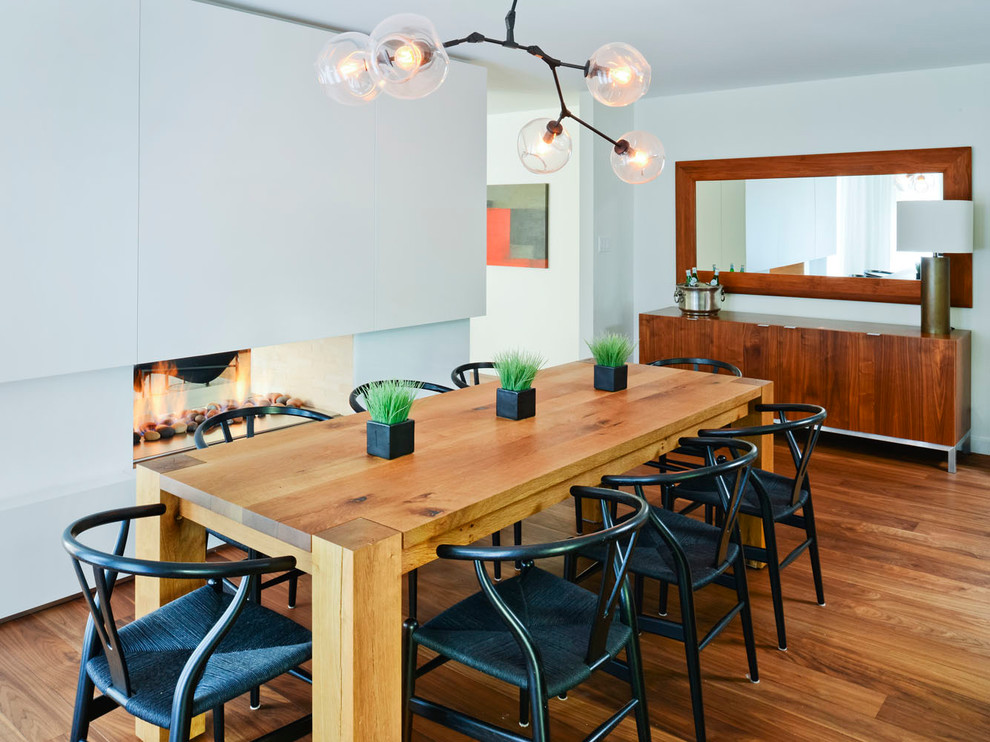 Immagine di una sala da pranzo minimal con pareti bianche, parquet scuro e camino bifacciale