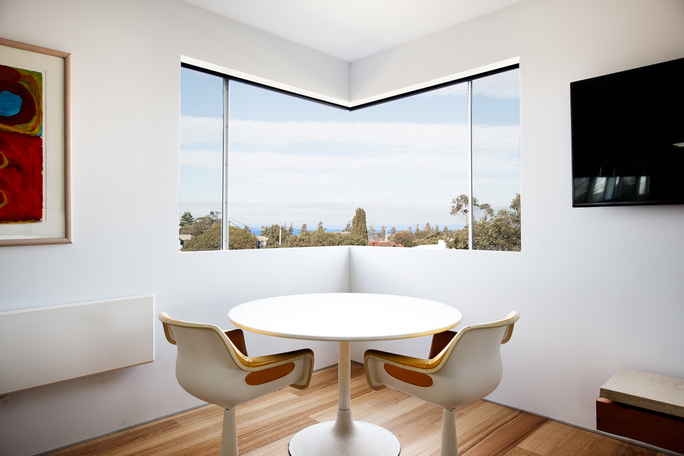Immagine di una piccola sala da pranzo aperta verso la cucina minimalista con pareti bianche e pavimento in legno massello medio