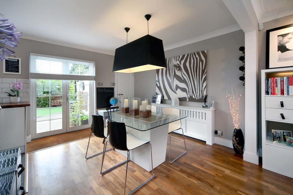 Cette image montre une salle à manger ouverte sur le salon design de taille moyenne avec un mur gris et un sol en bois brun.