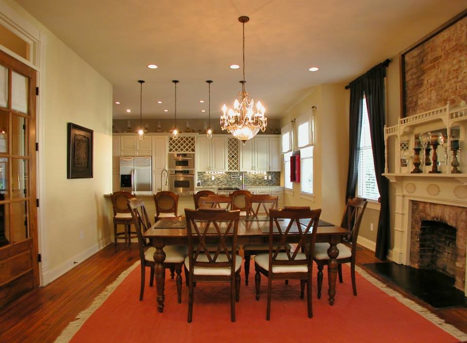 Réalisation d'une salle à manger ouverte sur la cuisine victorienne de taille moyenne avec un mur jaune, un sol en bois brun, une cheminée standard, un manteau de cheminée en brique et un sol marron.