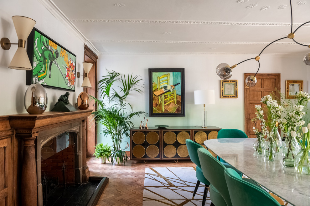 Cette image montre une grande salle à manger bohème fermée avec un mur vert, parquet clair, une cheminée standard, un manteau de cheminée en pierre, un sol beige et du papier peint.