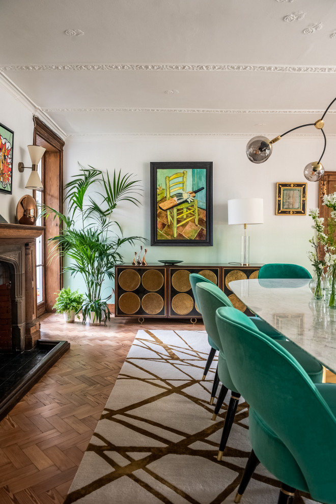 Large bohemian enclosed dining room in London with green walls, light hardwood flooring, a standard fireplace, a stone fireplace surround, beige floors and wallpapered walls.
