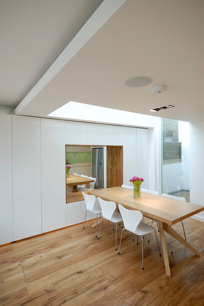 Inspiration pour une salle à manger design de taille moyenne avec un mur blanc et un sol en bois brun.