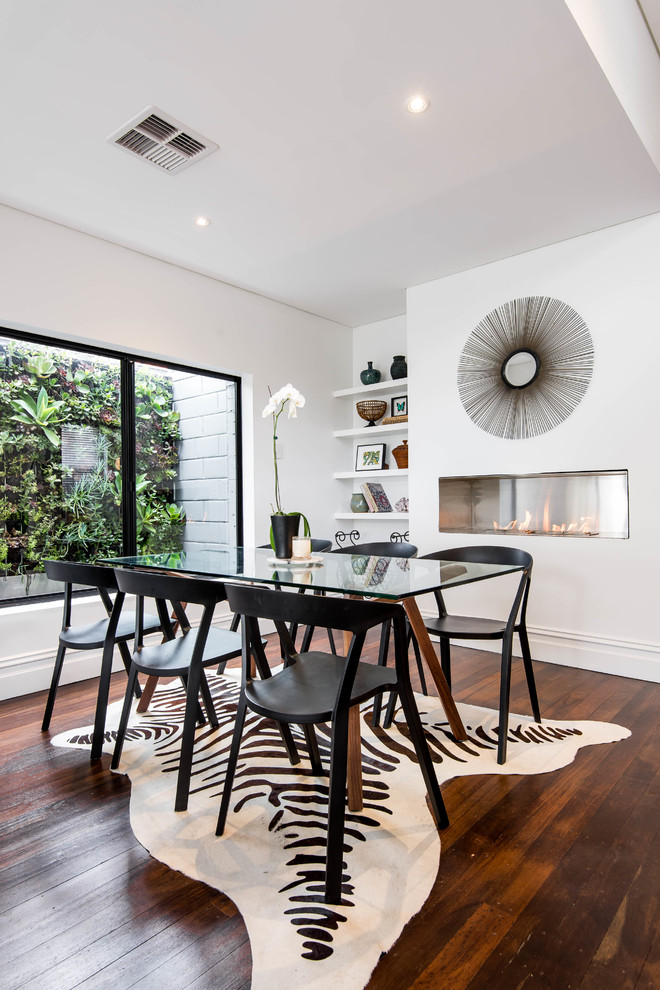 Example of a trendy dark wood floor dining room design in Perth with white walls and a ribbon fireplace