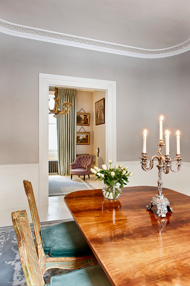 This is an example of a medium sized classic enclosed dining room in London with grey walls, a standard fireplace, a plastered fireplace surround and painted wood flooring.