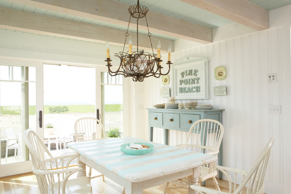 Immagine di una sala da pranzo aperta verso la cucina stile marinaro di medie dimensioni con pareti bianche, parquet chiaro e pavimento marrone