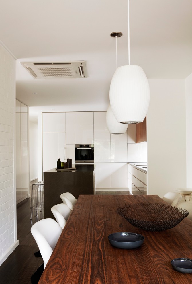 Inspiration pour une salle à manger ouverte sur la cuisine vintage avec un mur blanc et parquet foncé.
