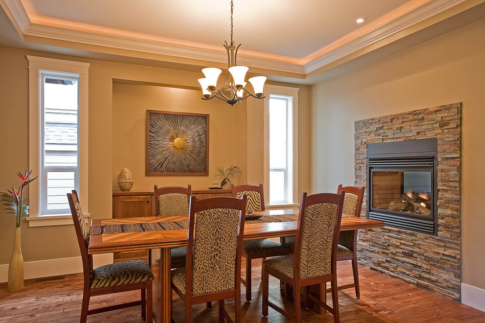 This is an example of a traditional dining room in Vancouver with a stone fireplace surround.