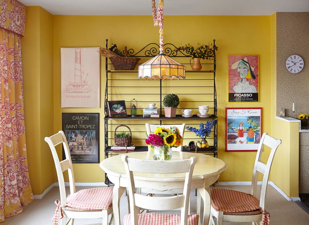 Immagine di una sala da pranzo aperta verso la cucina classica con pareti gialle e moquette