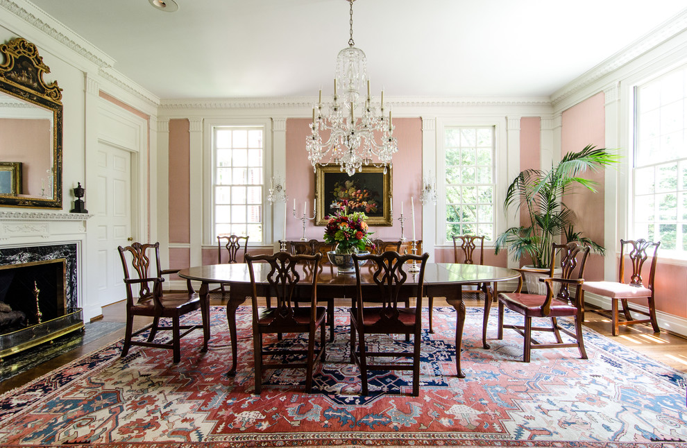 Imagen de comedor tradicional con paredes rosas, suelo de madera en tonos medios y todas las chimeneas