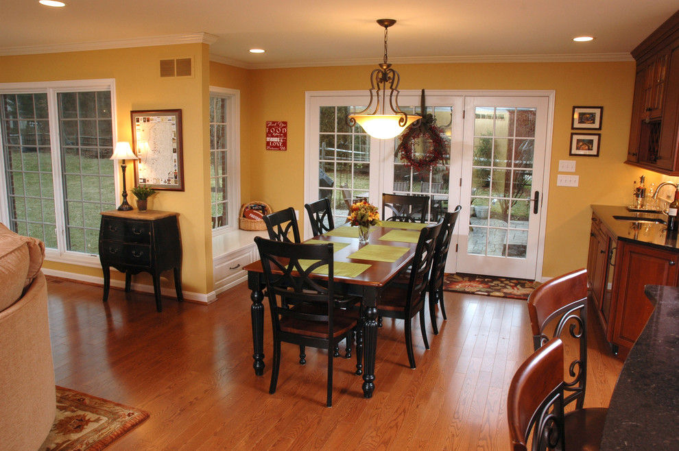 Réalisation d'une salle à manger ouverte sur le salon tradition de taille moyenne avec un mur jaune et un sol en bois brun.