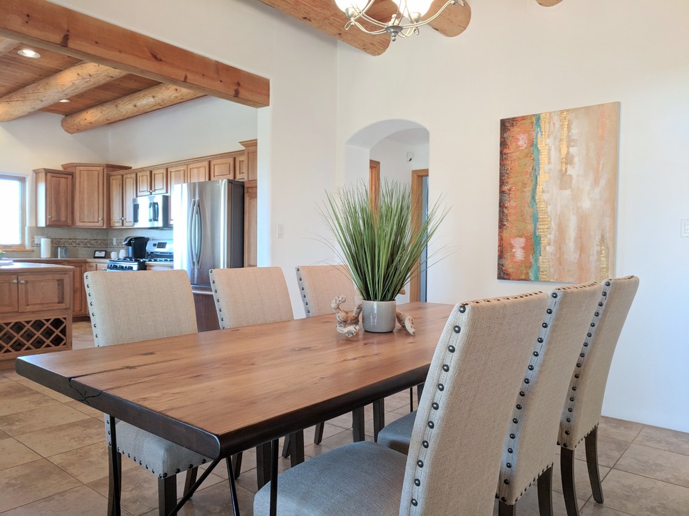 Aménagement d'une salle à manger ouverte sur la cuisine sud-ouest américain de taille moyenne avec un mur blanc, un sol en travertin, une cheminée d'angle, un manteau de cheminée en plâtre et un sol beige.