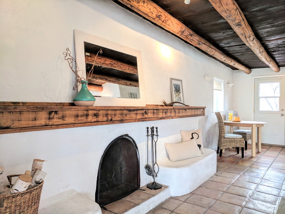 他の地域にある中くらいなサンタフェスタイルのおしゃれなダイニングキッチン (白い壁、テラコッタタイルの床、標準型暖炉、コンクリートの暖炉まわり、ベージュの床) の写真