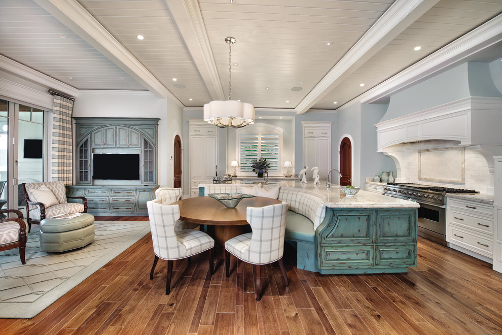 Cette photo montre une salle à manger ouverte sur la cuisine bord de mer de taille moyenne avec un mur bleu, parquet foncé, aucune cheminée et un sol marron.
