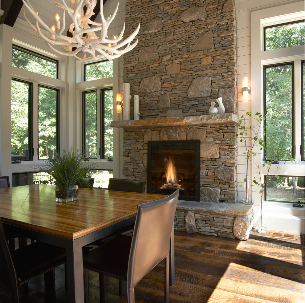 Exemple d'une salle à manger chic de taille moyenne avec un mur blanc, un sol en bois brun, une cheminée standard et un manteau de cheminée en pierre.