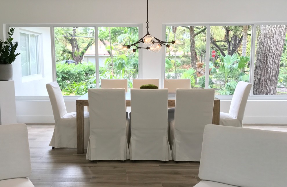 Immagine di una grande sala da pranzo aperta verso il soggiorno chic con pareti bianche, parquet chiaro, nessun camino e pavimento marrone