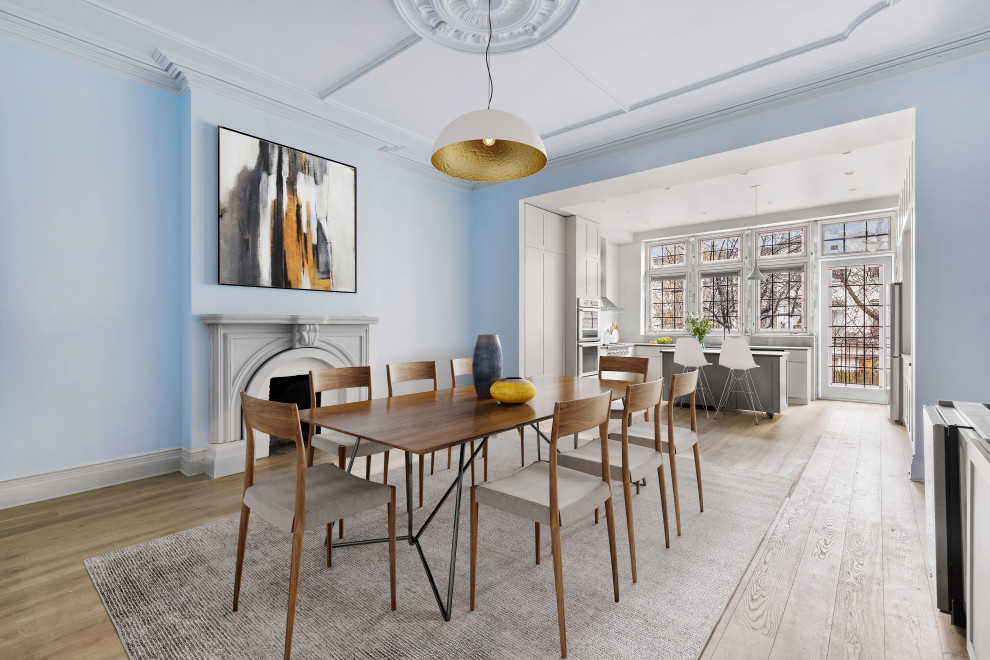 На фото: большая кухня-столовая в стиле неоклассика (современная классика) с синими стенами, светлым паркетным полом, стандартным камином, фасадом камина из бетона и бежевым полом с