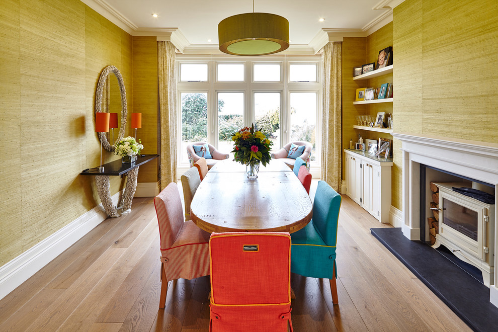 Пример оригинального дизайна: столовая в стиле неоклассика (современная классика) с желтыми стенами, светлым паркетным полом и печью-буржуйкой