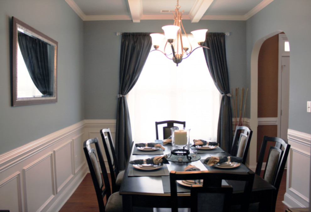 Cette photo montre une petite salle à manger chic fermée avec un mur bleu et un sol en bois brun.