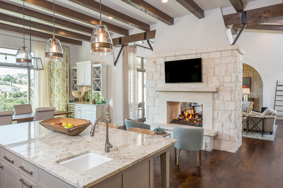 Große Landhaus Wohnküche mit weißer Wandfarbe, dunklem Holzboden, Tunnelkamin und Kaminumrandung aus Stein in Austin