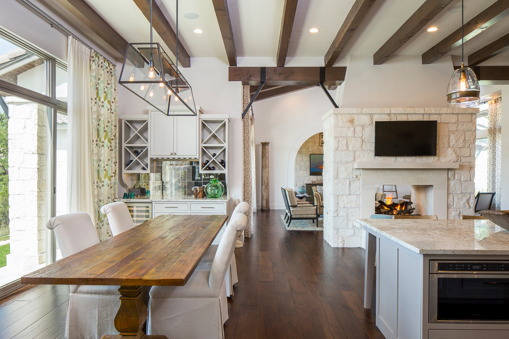 Große Landhaus Wohnküche mit weißer Wandfarbe, dunklem Holzboden, Tunnelkamin und Kaminumrandung aus Stein in Austin