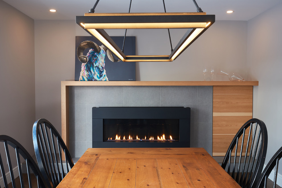 Inspiration for a mid-sized transitional medium tone wood floor and brown floor kitchen/dining room combo remodel in Edmonton with gray walls, a standard fireplace and a tile fireplace