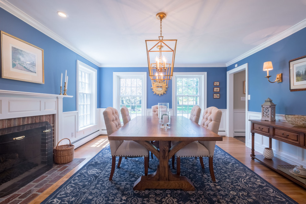 Geschlossenes, Mittelgroßes Klassisches Esszimmer mit blauer Wandfarbe, braunem Holzboden, Kamin, Kaminumrandung aus Holz und braunem Boden in Sonstige