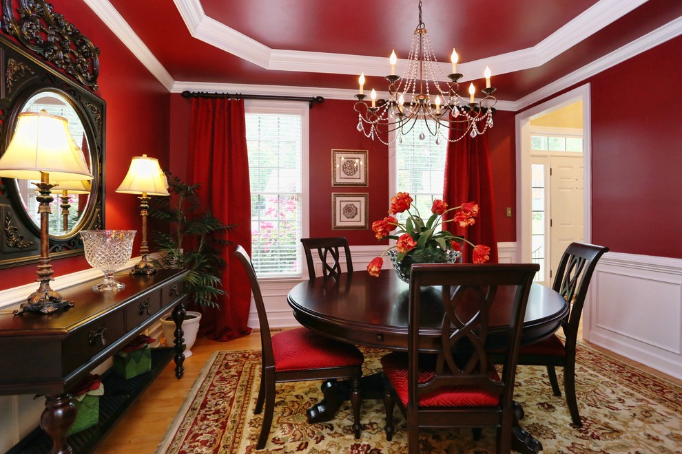 Immagine di una sala da pranzo tradizionale chiusa e di medie dimensioni con pareti rosse, pavimento in legno massello medio, nessun camino, pavimento marrone e soffitto ribassato