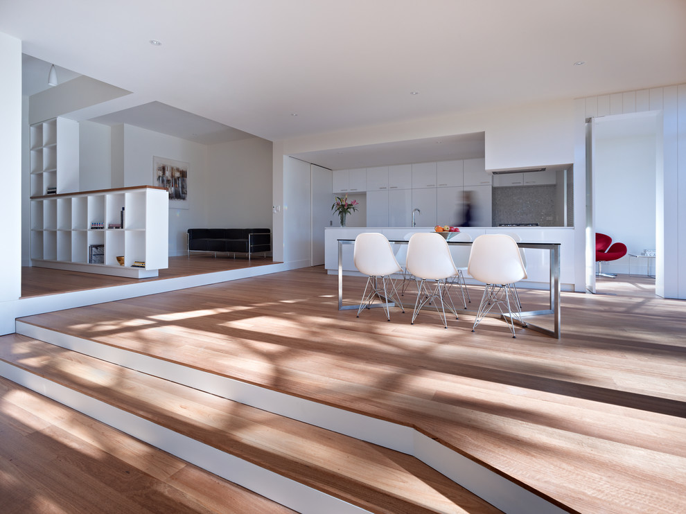 Inspiration pour une salle à manger ouverte sur la cuisine design de taille moyenne avec parquet clair et un mur blanc.