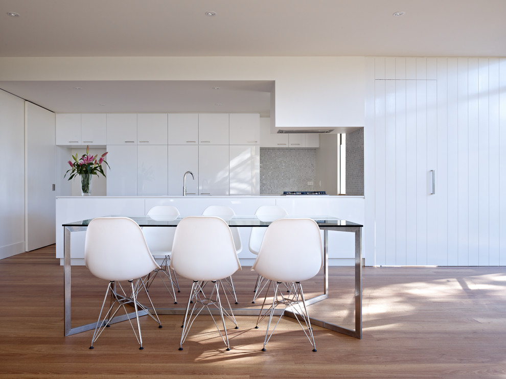 Immagine di una sala da pranzo aperta verso la cucina minimal con pareti bianche, pavimento in legno massello medio e pavimento marrone