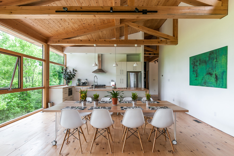 Exemple d'une salle à manger ouverte sur la cuisine tendance avec un mur blanc et parquet clair.
